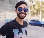 Portrait of a smiling man wearing sunglasses outdoors, showcasing modern fashion and style.